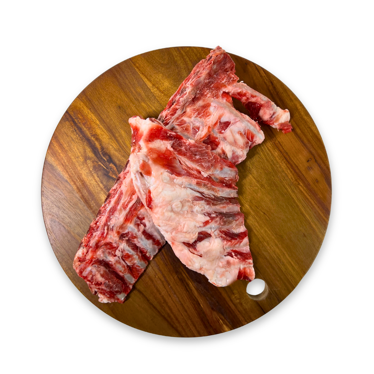 Two raw goat rib sections for raw feeding to dogs with visible bone and marbling, arranged on a round wooden cutting board against a plain white background.